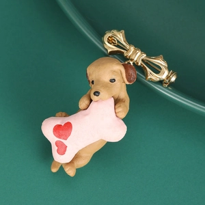 Detail of cute brown puppy enamel brooch with pink heart bone and gold bow tie