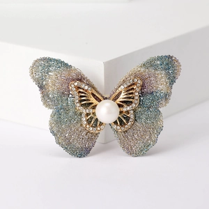 Détail macro d'une broche papillon avec ailes tissées dégradées et cristaux brillants