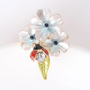 Vue détaillée de la broche fleur en émail avec coccinelle rouge et détails en cristal