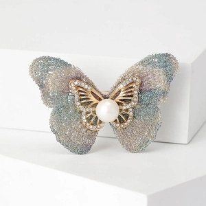 Élégante broche papillon avec perle et strass en cristal sur présentoir blanc