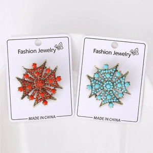 Vue détaillée des broches étoile vintage en rouge et turquoise sur carte de bijoux