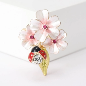 Détail de la broche fleur émaillée avec cerisier rose et motif coccinelle rouge