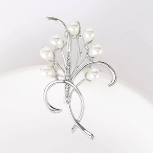 Dettaglio macro dell'elegante spilla a fiore con gambo d'argento e perle bianche lucide
