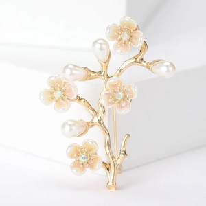 Macro dettaglio della spilla ramo di pesco dorato con perle e petali rosa cangianti