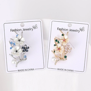 Detailed view of silver and gold flower brooches with pearls and colorful crystals