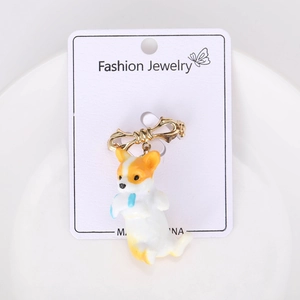 Detailed view of cute Corgi dog brooch with golden bow on a white jewelry display card