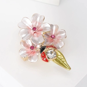 Détail de la broche fleur en émail avec fleurs roses et coccinelle en cristal