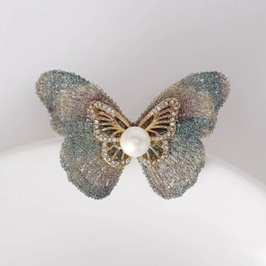 Gros plan détaillé de la broche papillon avec ailes en maille et perle centrale
