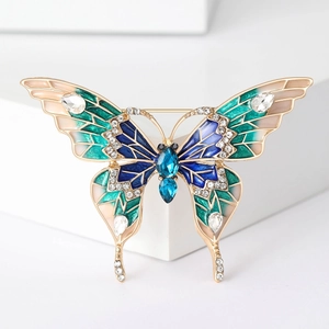 Gros plan détaillé de la broche papillon en émail bleu et vert avec cristaux sur fond blanc