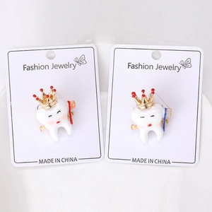 Detail view of dental tooth enamel pins with crowns and toothbrushes in red and blue colors