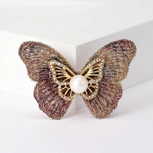 Détail d'une broche papillon en maille violette avec perle centrale et cristaux