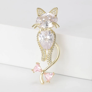 Elegant gold cat brooch with sparkling zircon stones and pink bow on white background