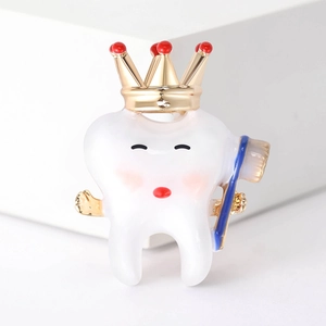 Detail of creative tooth enamel pin with golden crown and blue toothbrush accessory