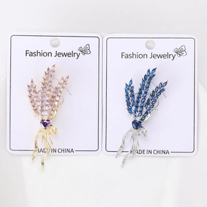 Macro detail of wheat ear brooches with cubic zirconia and heart charms on display cards
