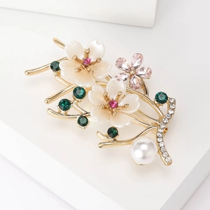 Macro shot of elegant gold flower brooch with white petals, pink crystal and round pearl