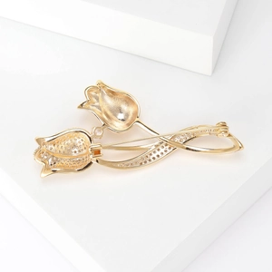 Elegant gold-plated double tulip brooch with micro-pave cubic zirconia on a white pedestal