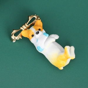 Close-up of a cute cartoon Corgi dog brooch with golden bow clip on dark green texture