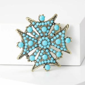 Broche étoile vintage dorée avec incrustations de turquoise sur socle blanc