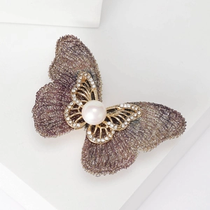 Détail de la broche papillon en tissu violet avec perle blanche et petits cristaux