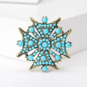 Détail d'une broche étoile vintage avec perles turquoise et finition en bronze