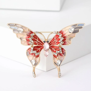 Gros plan détaillé d'une broche papillon en métal doré, émail rouge et strass brillants