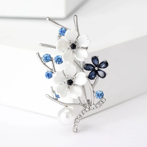 Detail of floral brooch with enamel flowers, blue rhinestones, and hanging pearl pendant