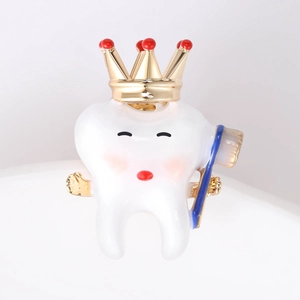 Close-up of cute cartoon tooth brooch with gold crown and blue toothbrush accessory