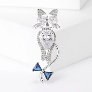 Macro shot of silver cat brooch with white gemstones and blue crystal bow details