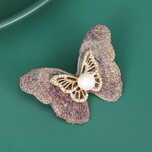 Détail de l'élégante broche papillon en maille violette et or avec perle et strass
