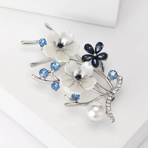 Close-up of elegant pearl flower brooch with blue rhinestones and silver branch details