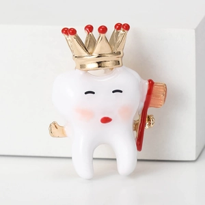 Creative white enamel tooth brooch with a golden crown and mini toothbrush accessory
