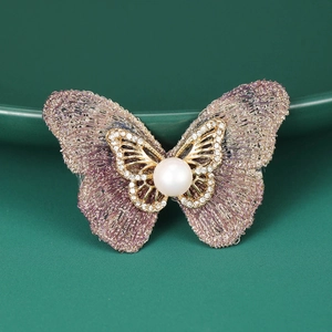 Détail de la broche papillon en broderie avec perle blanche et strass étincelants