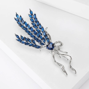 Macro detail of wheat ear brooch with blue marquise stones and heart-shaped center