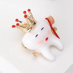 Macro detail of tooth brooch with gold crown and enamel finish for clothes decoration