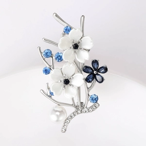 Detailed view of elegant silver floral brooch with pearls, blue rhinestones and enamel flowers