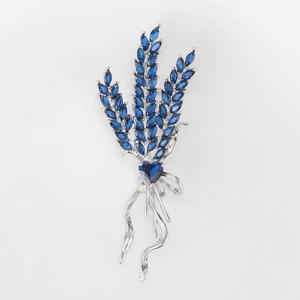 Detailed view of silver wheat brooch with deep blue marquise-cut zircon stones