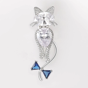Detail of a cat brooch with inlaid zircons and a blue crystal bow on white background