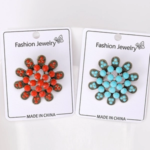 Détail de broches fleurs vintage en bleu turquoise et orange sur cartes de présentation
