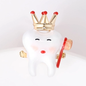 Macro detail of cartoon tooth enamel pin with a gold crown and tiny red toothbrush