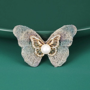 Détail de la broche papillon avec ailes en maille, strass et perle élégante
