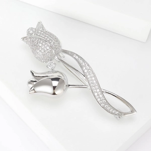 Macro shot of tulip brooch with pave-set zircon flower and polished metal leaf detail