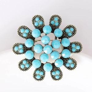 Détail d'une broche tournesol vintage avec pierres turquoise et base dorée antique