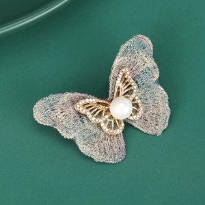 Détail d'une broche papillon élégante avec des ailes en maille translucide et des cristaux