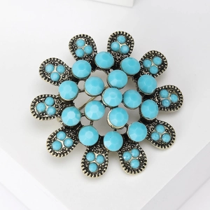 Gros plan sur une broche fleurie vintage en bronze avec perles bleu turquoise serties
