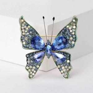 Makroaufnahme einer Schmetterlingsbrosche mit blauen Kristallen und Strass auf weißem Fuß