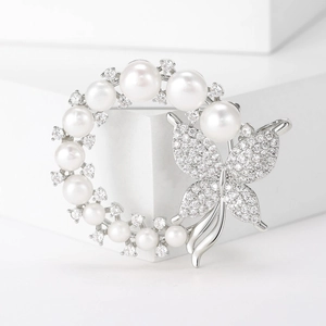 Macro shot of silver wreath brooch with white freshwater pearls and zircon butterfly