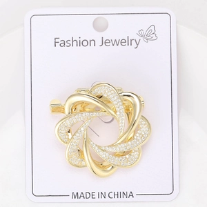 Détail d'une broche fleur dorée avec micro-pavé de zircons et un design en spirale