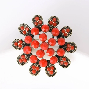 Détail d'une broche fleur dorée vintage avec pierres rouges et perles de rocaille