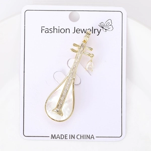 Macro detail of golden Pipa brooch with mother of pearl inlay and sparkling zircons