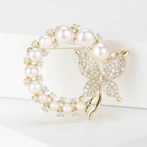 Close-up of pearl brooch with zircon-encrusted butterfly and polished gold finish